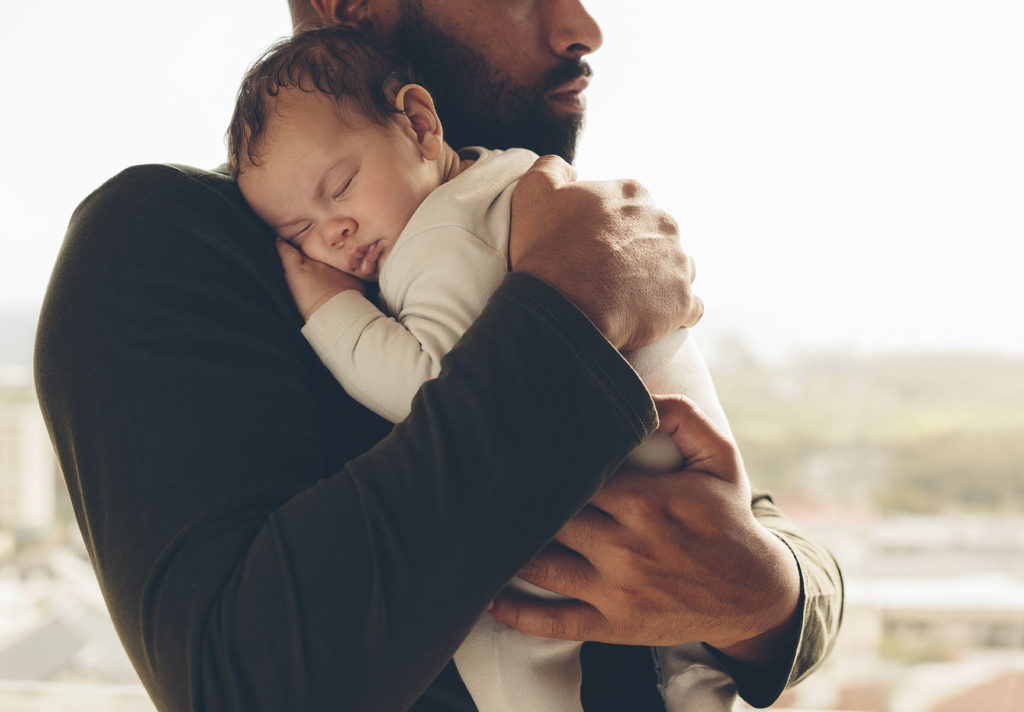 Man carrying his sleeping son. Newborn baby boy in his father's arms.